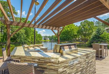 Outdoor kitchen with bar seating and tables overlooking lake heatherbrooke